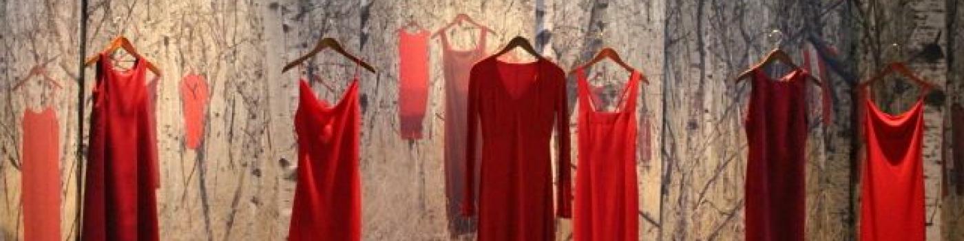 A series of red dresses hanging up in a display for the REDress Project